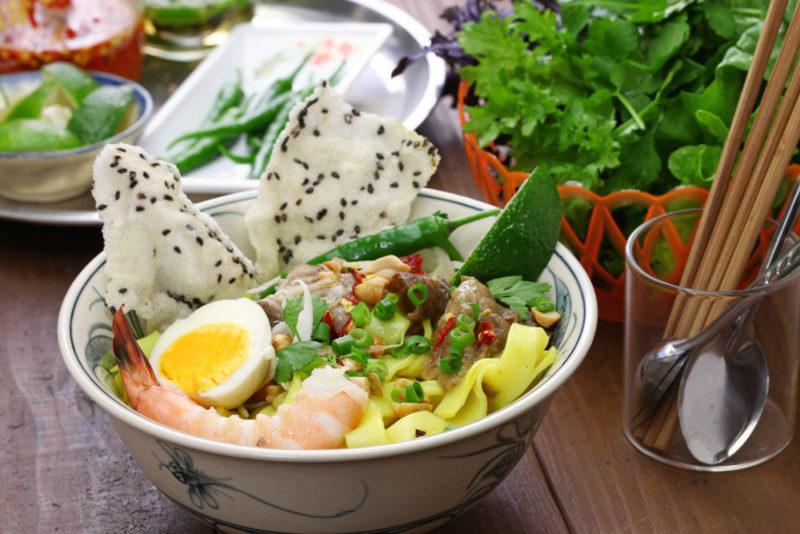 A bowl of mi quang with many fresh ingredients