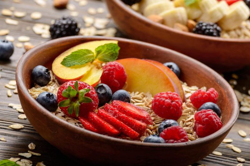 Two brown bowls that are filled with museli and fruit