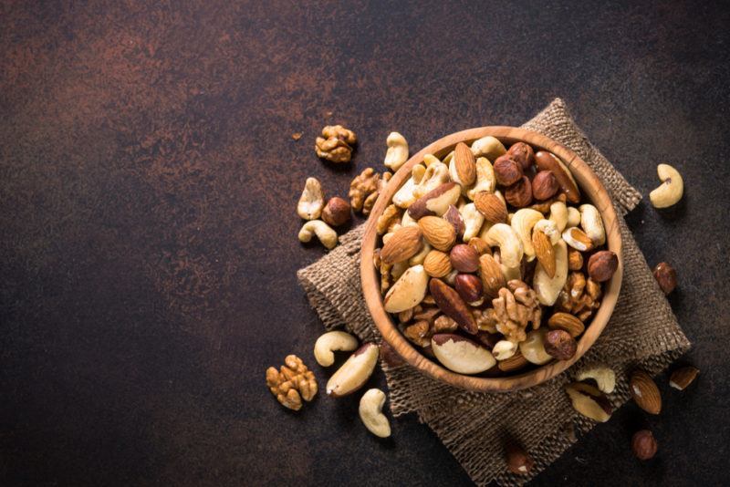 A wooden bowl filled with a large selection of nuts