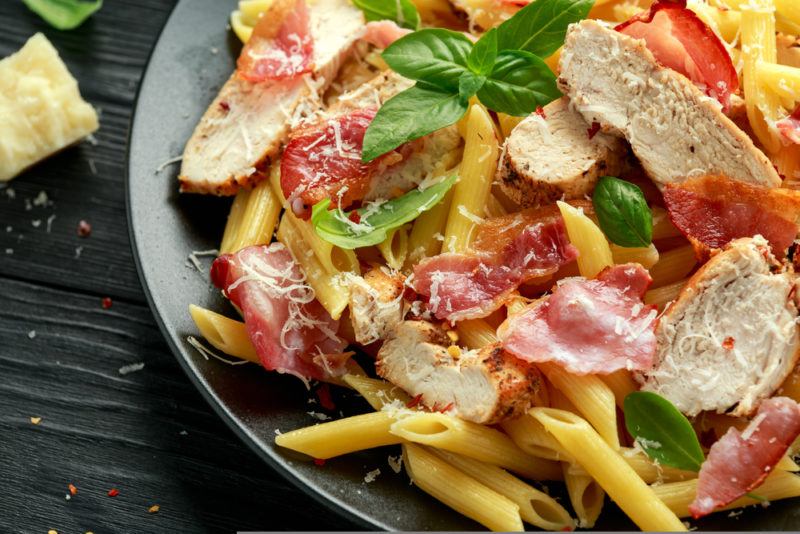 A gray bowl of penne boscailoa on a black table