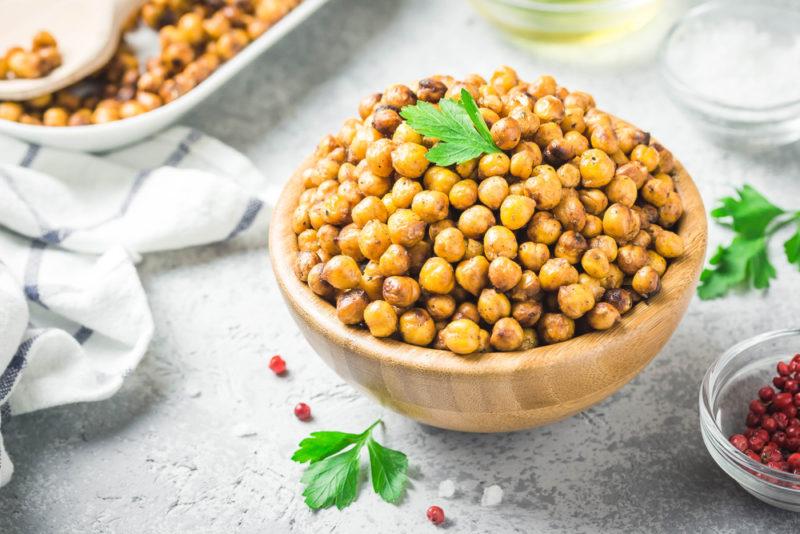 A wooden bowl filled with roasted chickpeas