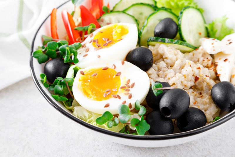 A black and white bowl with a savory oatmeal meal