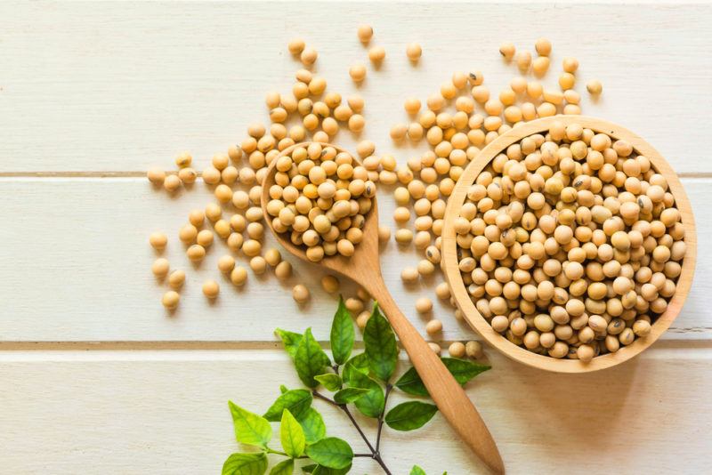 A wooden bowl of soybeans and a wooden spoon of the beans