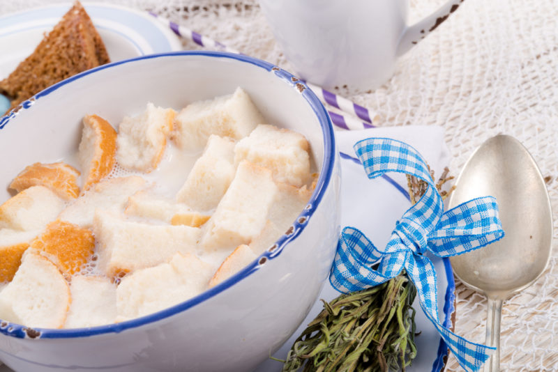 A blue and white bowl of bread soaked in sweet milk