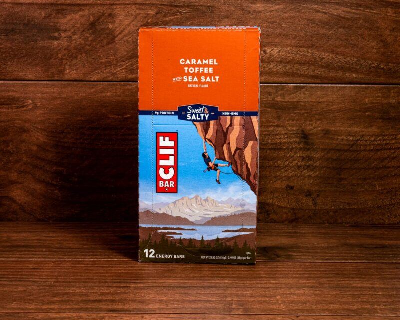 A box of Clif bars on a wooden floor against a wooden wall