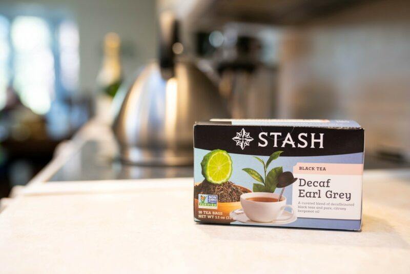 A box of Stash decaf tea on a kitchen counter, with an out of focus kettle in the background