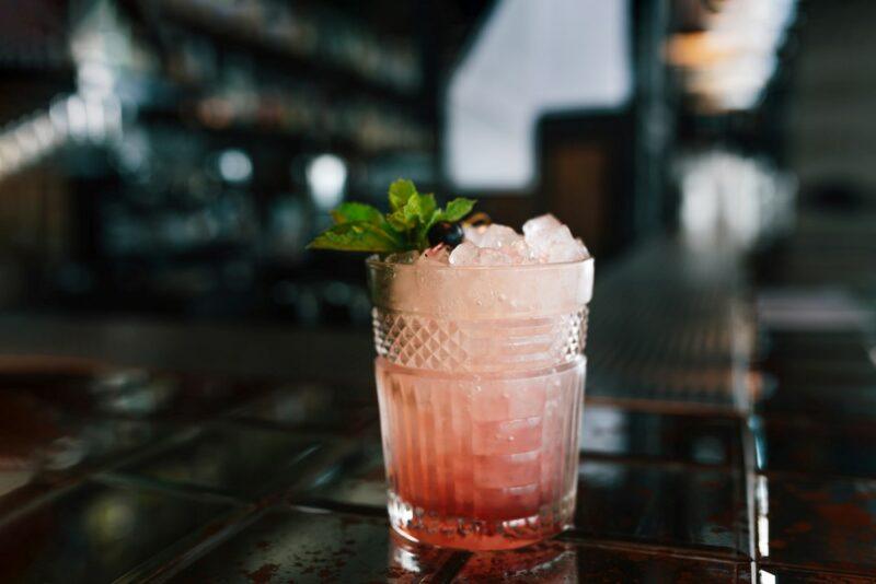 A cocktail glass containing a bramble cocktail with plenty of ice