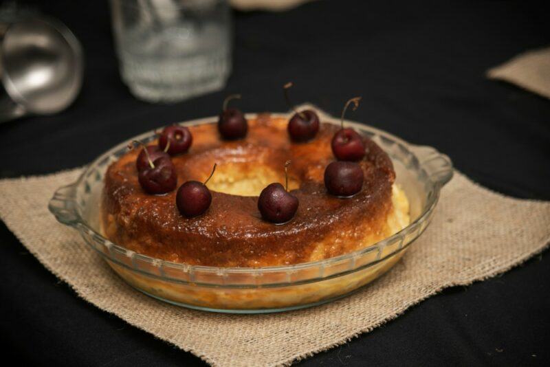 A glass dish containing a bread pudding called budin with cherries on top