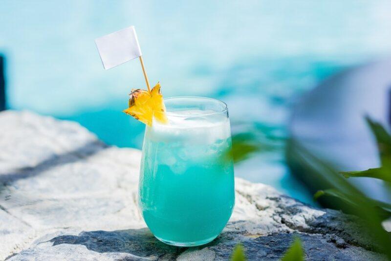 A glass containing a bright blue bullfrog cocktail on rocks