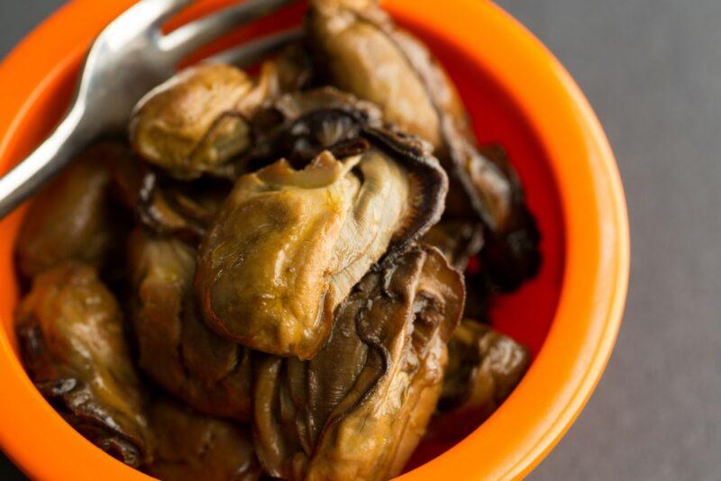 An orange bowl filled with smoked oysters