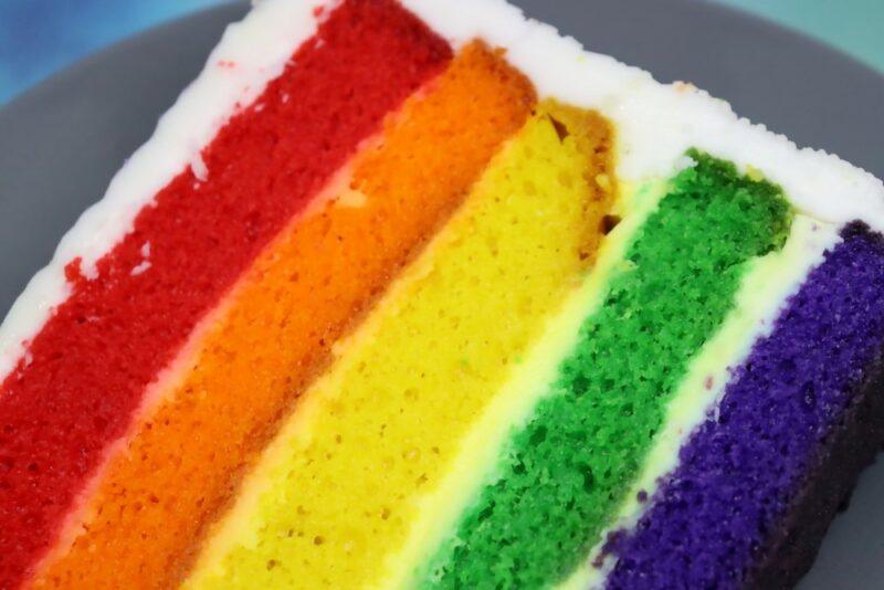 A layered rainbow cake that has been made using artificial food coloring