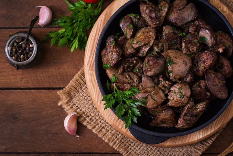 A light brown bowl with cooked liver, next to seasonings