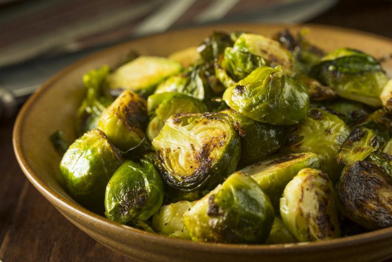 A brown bowl that contains cooked Brussels sprouts