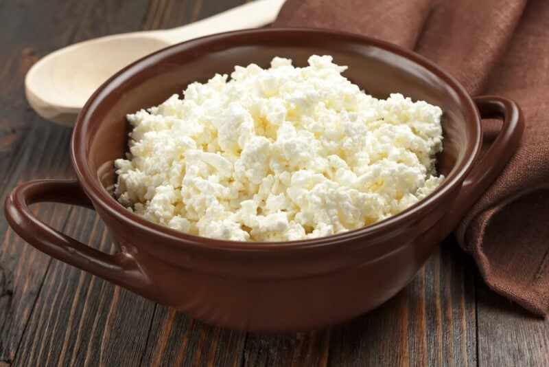 A large dish filled with cottage cheese, in front of a wooden spoon