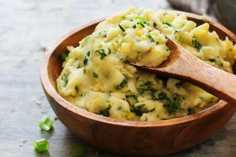 A brown bowl containing mashed potatoes with herbs