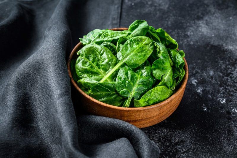 A wooden bowl of spinach leaves