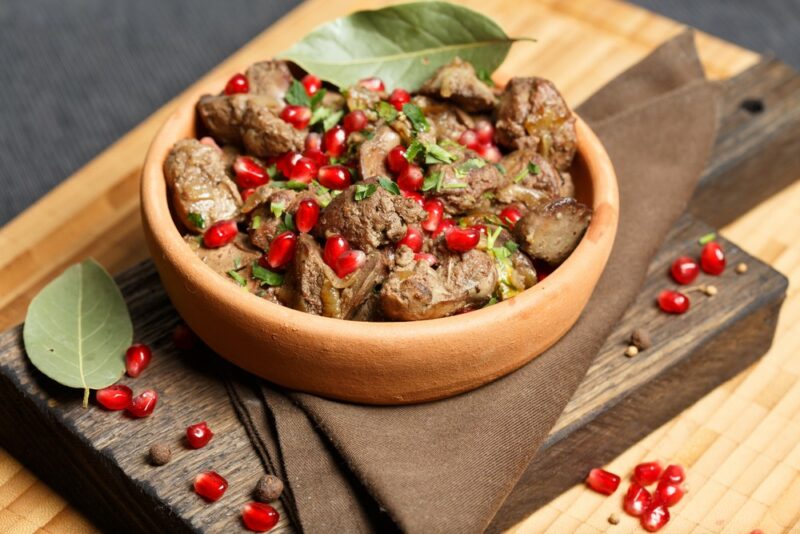 A small bowl containing cooked chicken livers and pomegranate arils