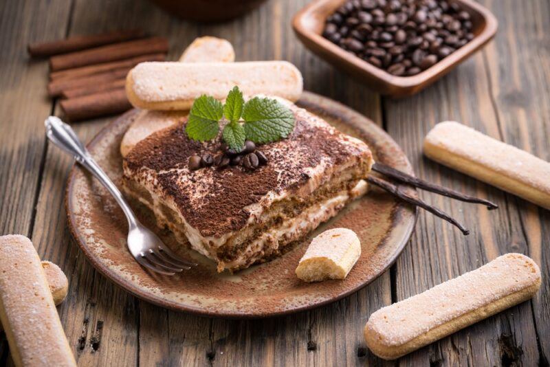 A brown plate on a wooden table with tiramisu and lady fingers