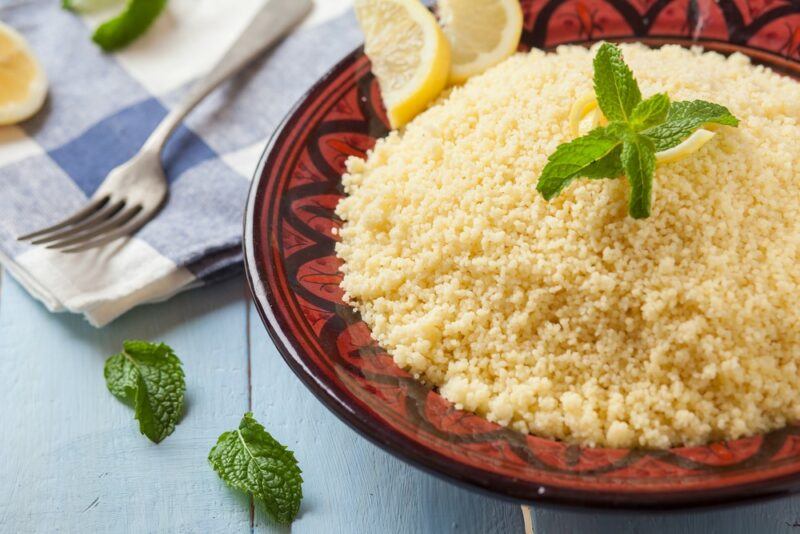 A black and red dish with a large collection of couscous