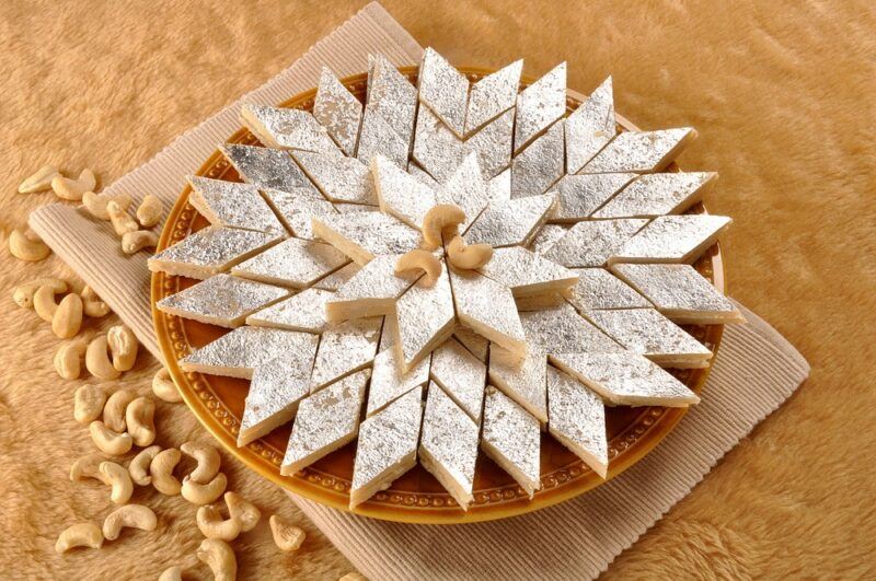 A brown plate with triangular kaju katli treats arranged in a star pattern