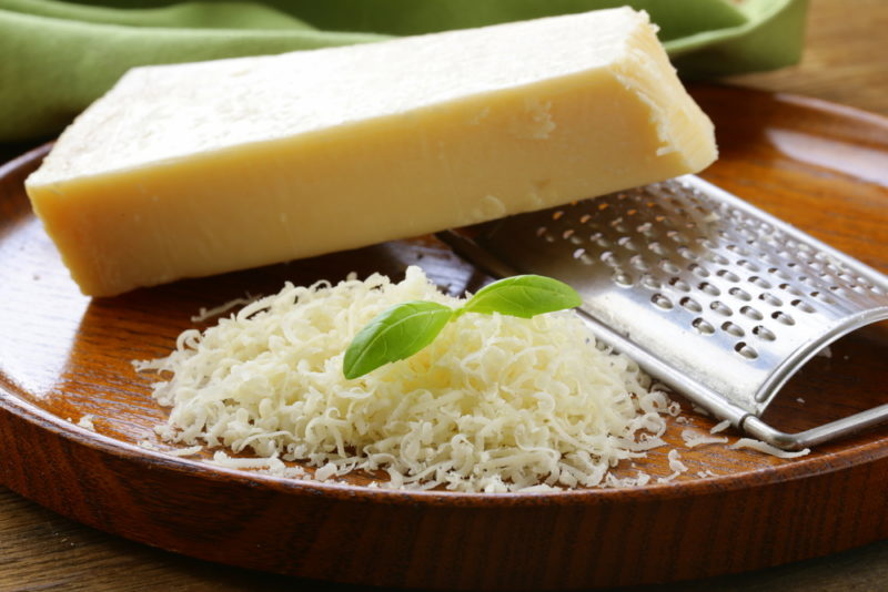 A brown plate with a block of parmesan, a grater, and some grated parmesan