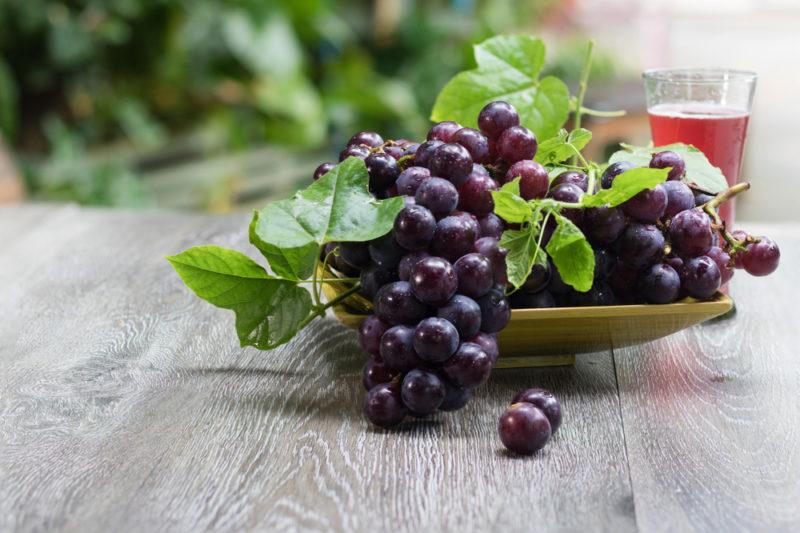 Dark grapes on a wooden plate