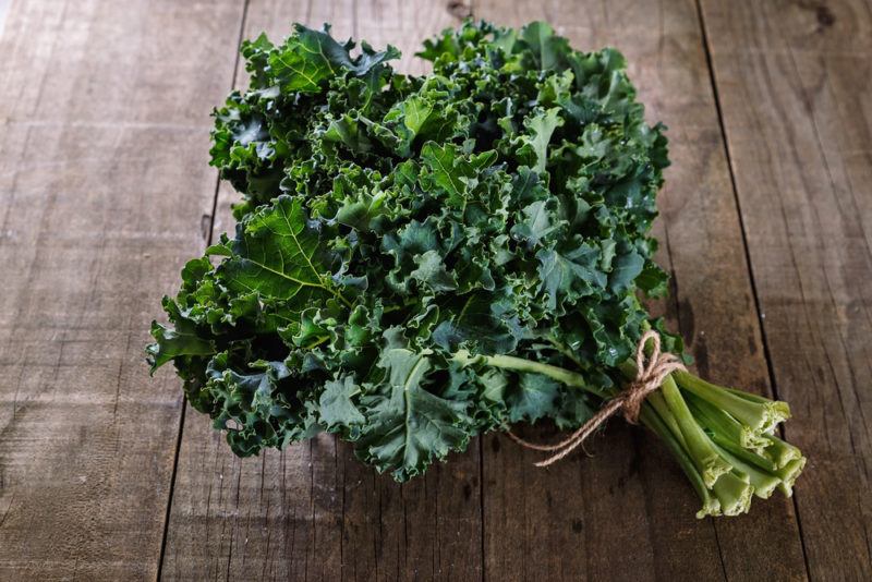 A bundle of curly kale tied up on a wooden floor