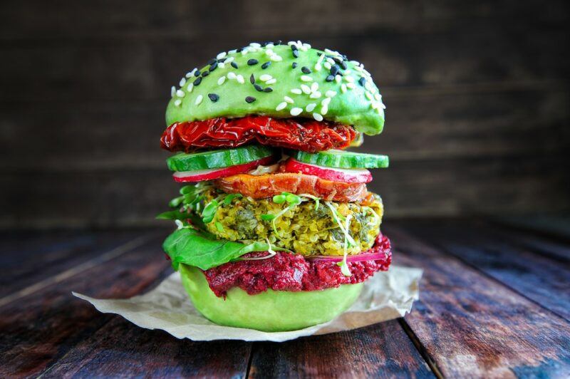 A tall vegan burger, made using avocado halves instead of burger buns