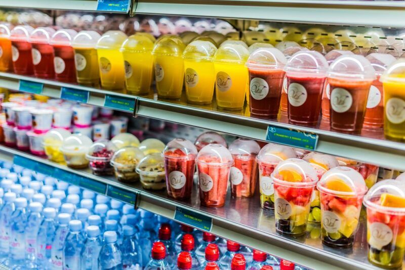 A chiller with desserts and snacks at an airport, including fruit salad