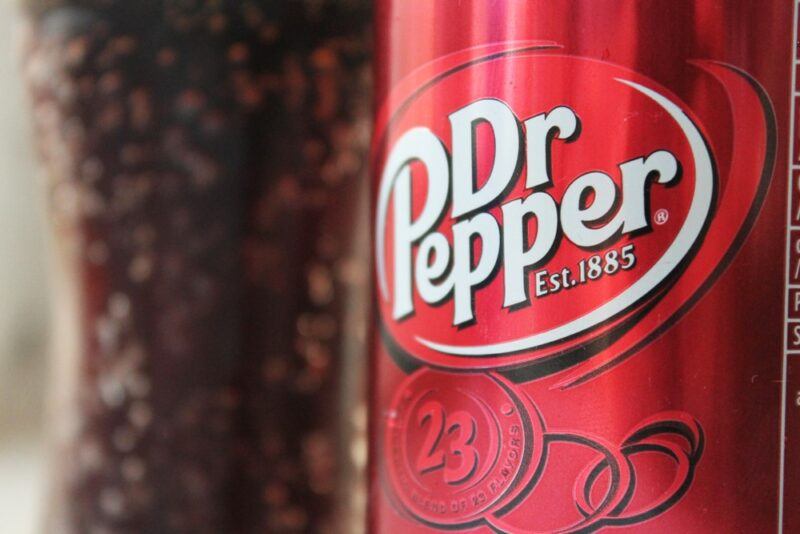 A can of Dr. Pepper with the label clearly showing, next to a glass of the soda