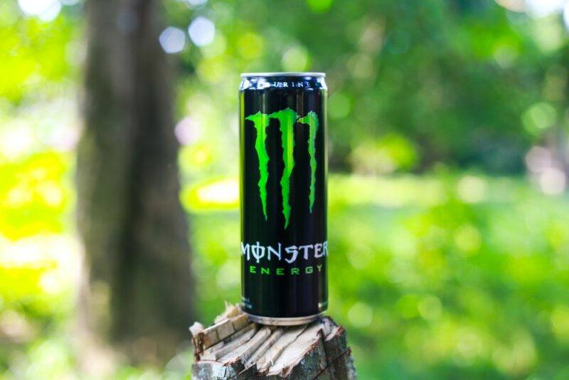 A can of Monster energy drink sitting outside in an out of focus park