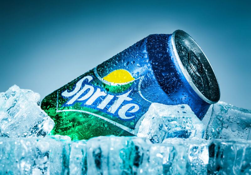 A single can of Sprite lying down on ice cubes