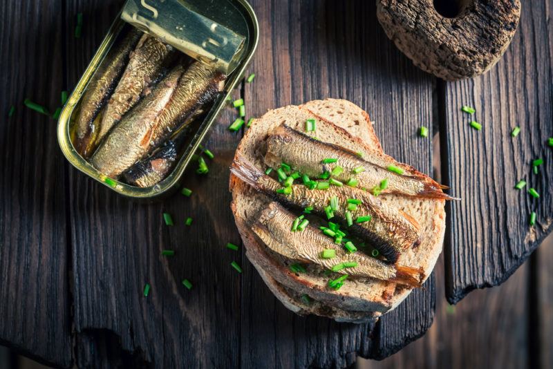 A can of sardines, next to sardines on a roll