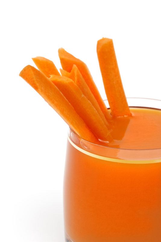 A carrot juice cocktail with carrot sticks as a garnish