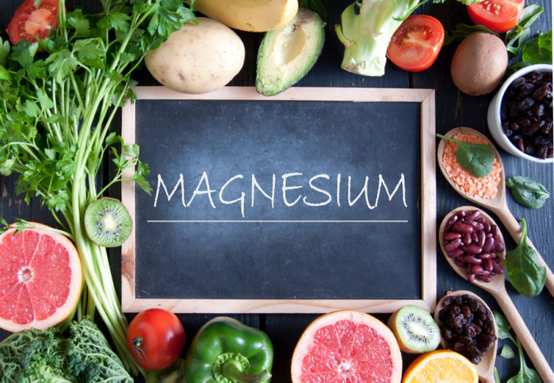 Various magnesium foods surrounding a chalkboard with veggies and fruits