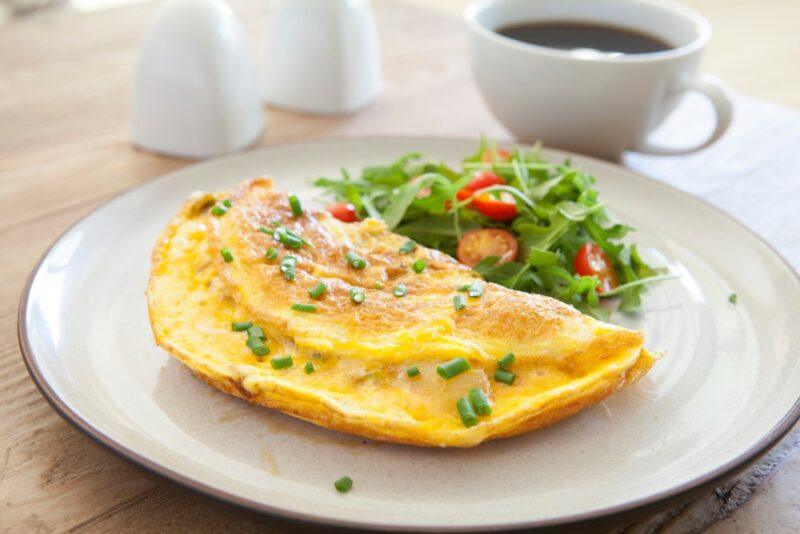 A white plate with a cheese omelet and a salad