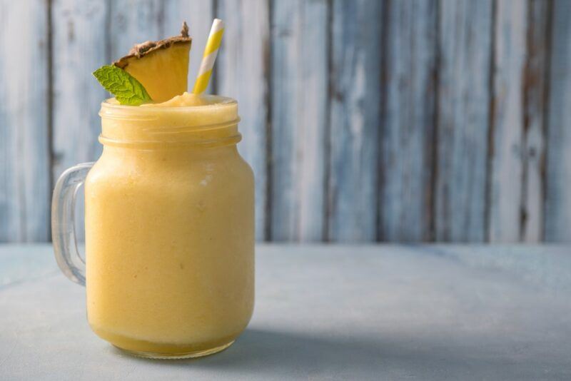 A mason jar containing a chi chi cocktail with a pineapple wedge