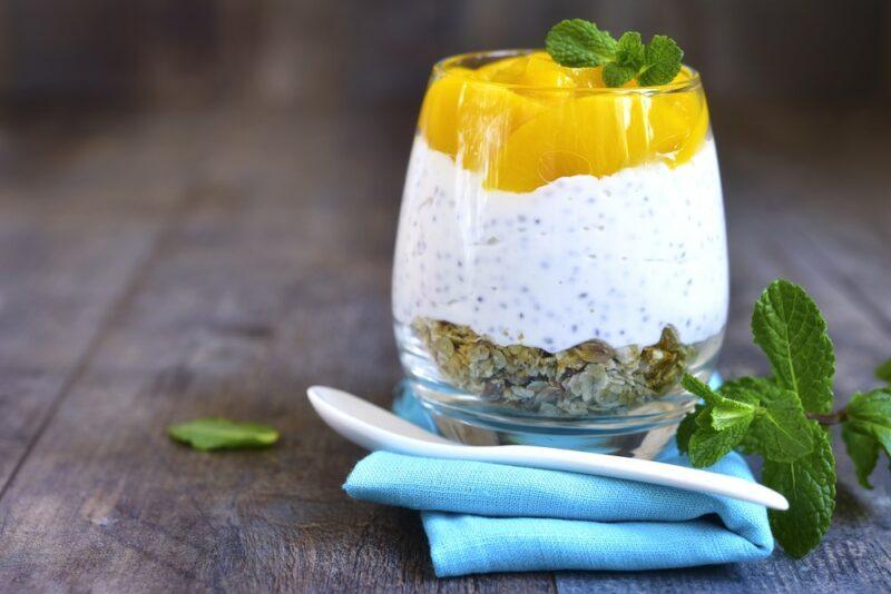 A glass of a chia pudding dessert with peaches and yogurt