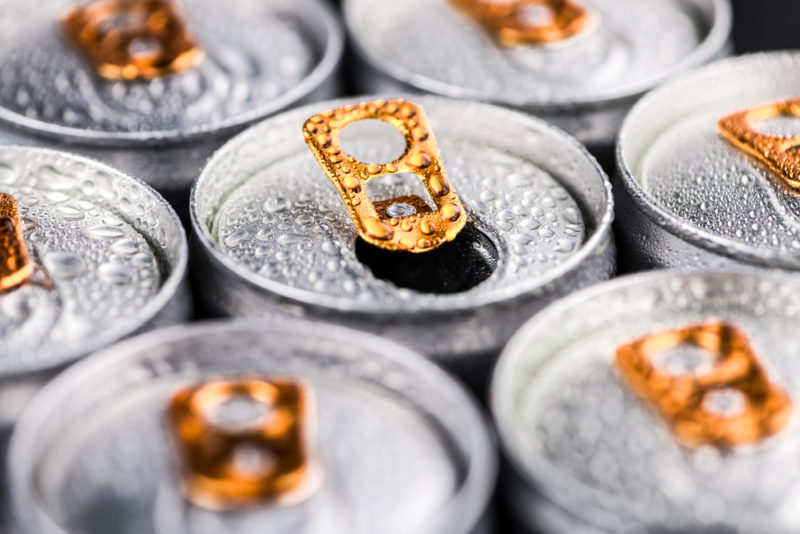 The tops of seven energy drink cans with some condensation