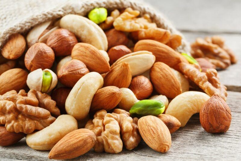 A cloth bag filled with many different types of nuts, including almonds and pistachios