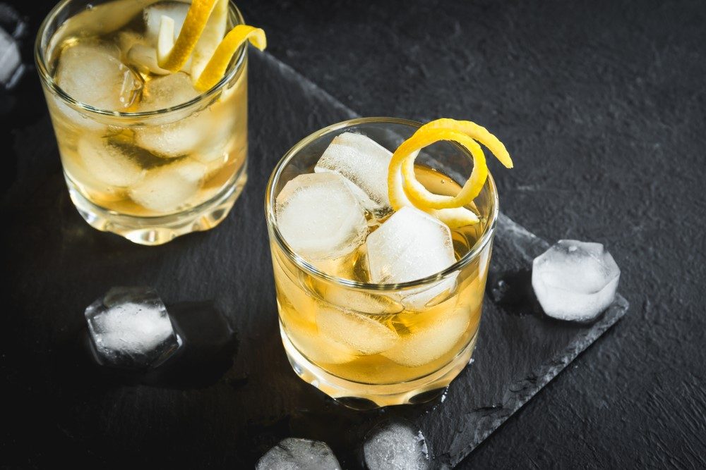 A black table with pieces of ice and two cocktails called an evening in Mexico