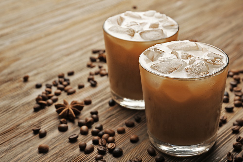 A cocktail called the Mexican iced coffee on a table with plenty of coffee beans