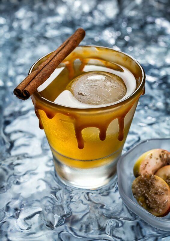 A glass containing a salted caramel gin cocktail with a cinnamon stick