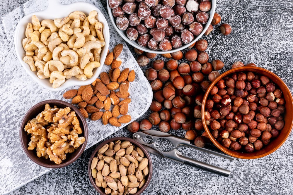 Bowls of different types of nuts, including almonds and cashews