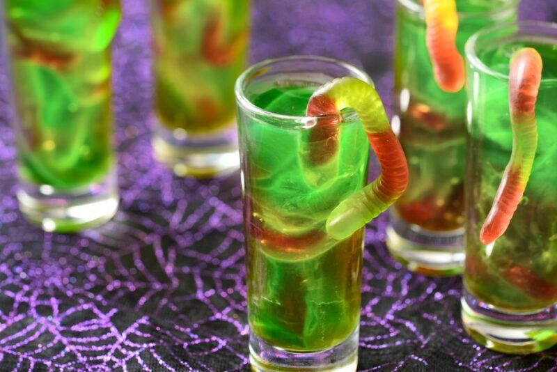 Green jello shots with gummy works on a purple table