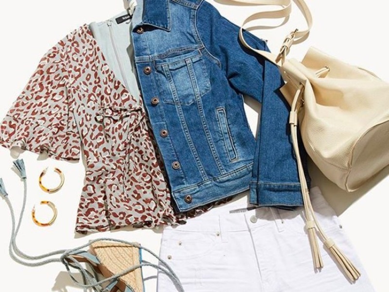 A complete outfit with accessories, leopard print top, denim jacket, white shorts, off-white purse, wedge sandals, and hoop earrings on a white background