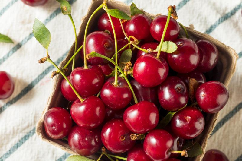 A wooden contain filled with a selection of tart cherries