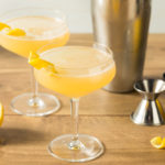 Two gin corpse reviver cocktails next to a cocktail jigger and shaker