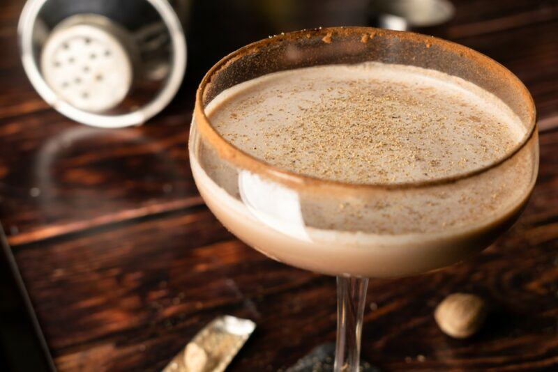 A coupe glass containing a brandy Alexander cocktail that has been rimmed with cinnamon or chocolate