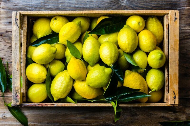 A crate of fresh lemons on a wooden table